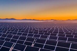Photo depicts and aerial view of hundreds solar energy panels rows along the dry lands at Atacama Desert, Chile. Huge Photovoltaic PV Plant in the middle of the desert from an aerial drone point of view during sunset